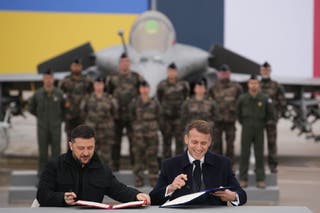 French President Emmanuel Macron, right, and Ukrainian President Volodymyr Zelenskyy sign an agreement Monday